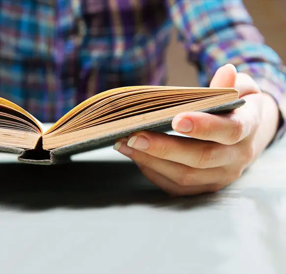 A person reading a book on top of a table.