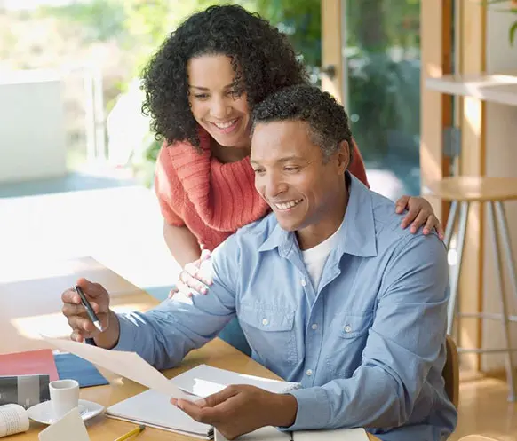 A man and woman sitting at a table with papers.