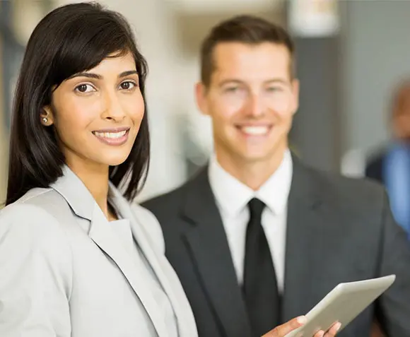 A woman and man in business attire holding a tablet.